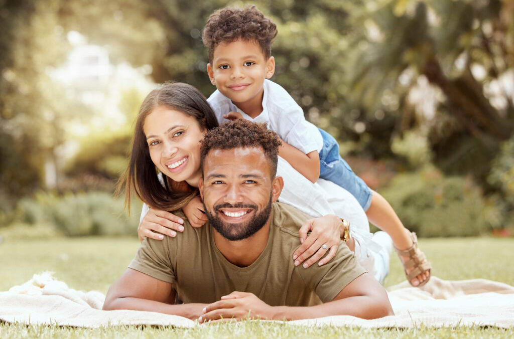 Relax, smile and picnic with portrait of family in park for summer, happy and nature. Wellness, spring and health with other and father embrace with child in grass field or countryside environment.
