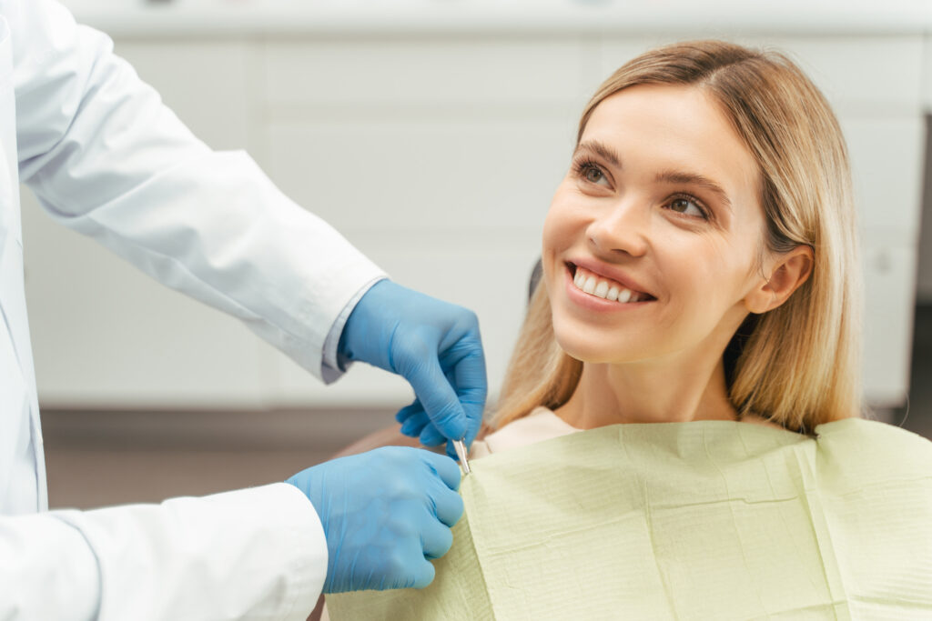 Portrait of smiling beautiful female patient with blond hair sitting in dental chair. Attractive young woman visiting modern clinic. concept of dental care